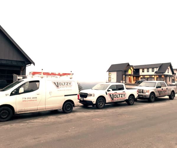 three Voltzy Electric branded vehicles parked on street
